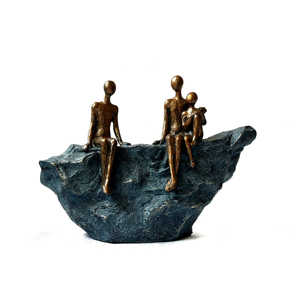 Escultura de familia de tres sentada en roca